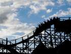 Silhouette of people raising their hands on a roller coaster. Art Print
